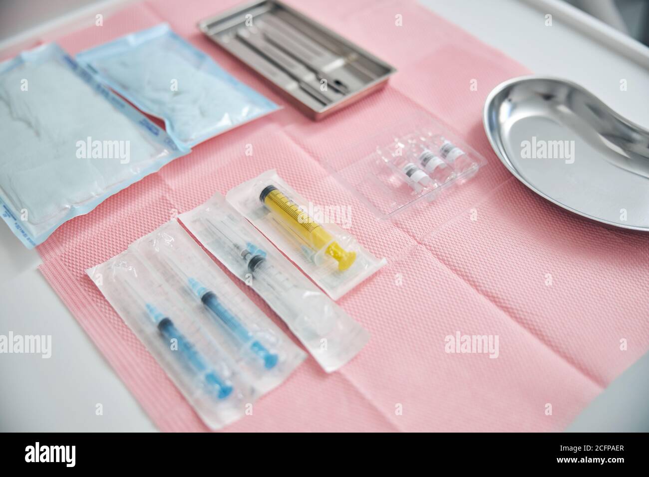 Edelstahlschalen zwischen versiegelten Spritzen und Gazepads Stockfoto