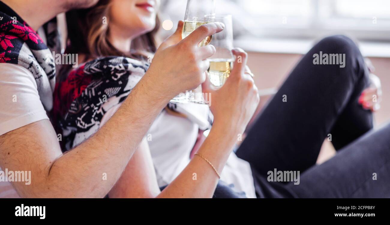 Mann und Frau in weißen T-Shirts und Strickpullover halten Gläser Champagner in den Händen Stockfoto