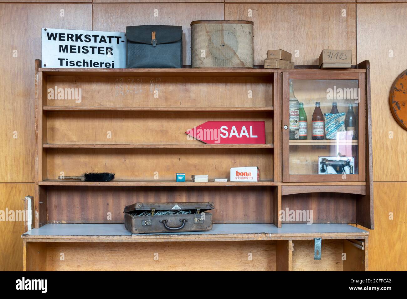 04. September 2020, Sachsen-Anhalt, Magdeburg: In einem Holzregal steht ein Schild mit dem Ruf Werkstatt-Meister Tischlerei. Daneben gibt es eine Tasche und einen alten Lautsprecher, darunter einen Koffer. Die Objekte gehören zum Inventar der Stadthalle, die vollständig verkauft werden sollen. Das Gebäude soll dann innerhalb von drei Jahren renoviert werden. Kosten: Rund 70 Millionen Euro. Das Gebäude wurde zwischen 1926 und 1927 anlässlich der Deutschen Theaterausstellung im Stil des Neuen Bauens errichtet. Die Architekten waren Johannes Göderitz und Wilhelm Deffke. Foto: Stephan Schulz/dpa-Zentralbild/ZB Stockfoto