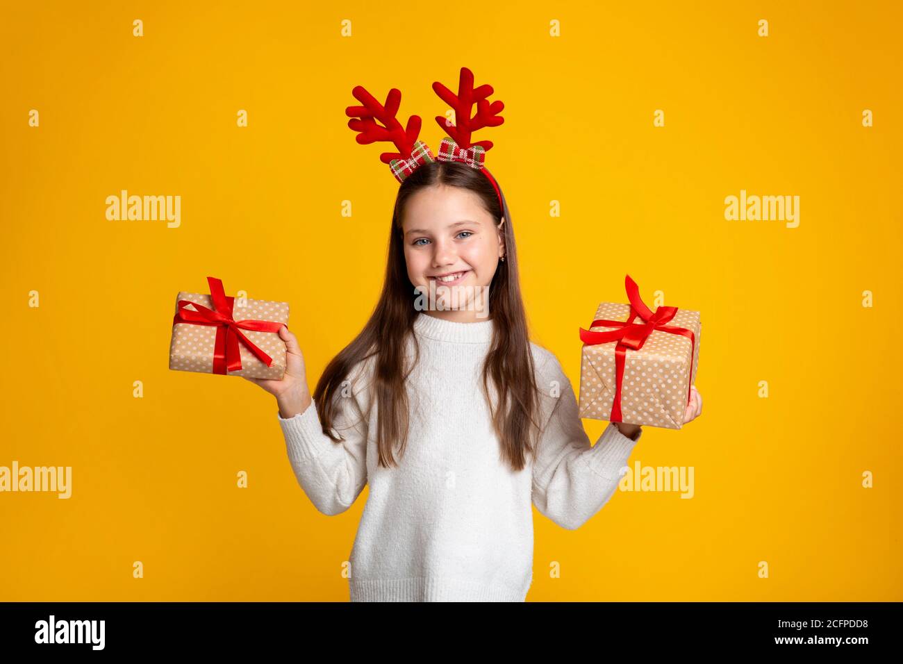 Kindheit, Weihnachten und Stimmung. Lächelndes Kind, das zwei Geschenke in ihren Händen hält Stockfoto