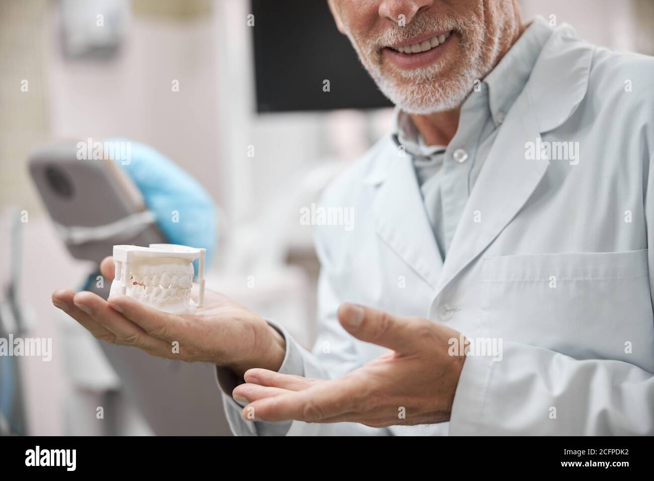 Smiley Zahntechniker hält eine Gipsform der Kiefer Stockfoto