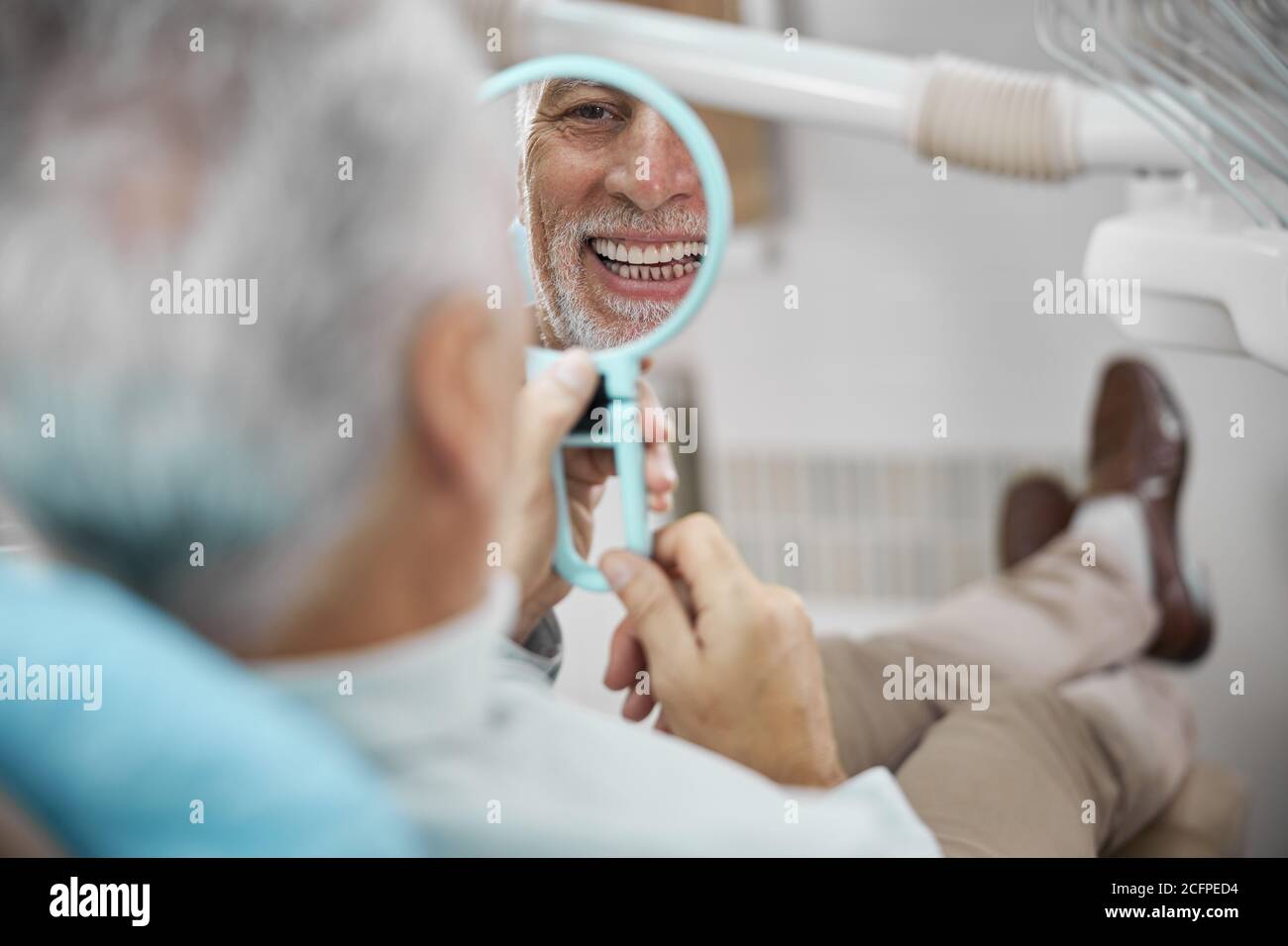 Eldelry Mann, der in den Spiegel schaut und lächelt Stockfoto