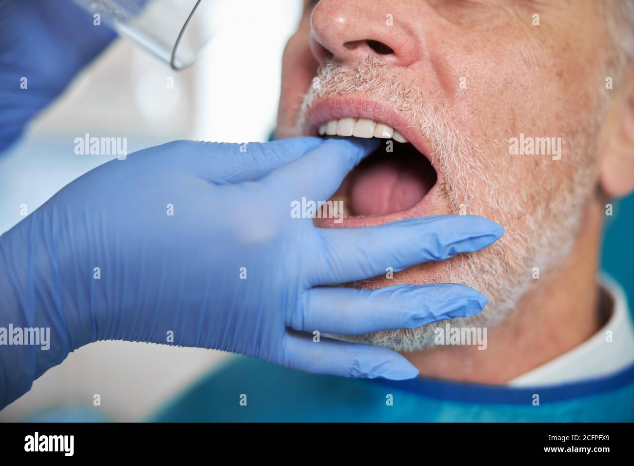 Alternder Mann, der seinen Mund für einen Zahnarzt offen hält Stockfoto