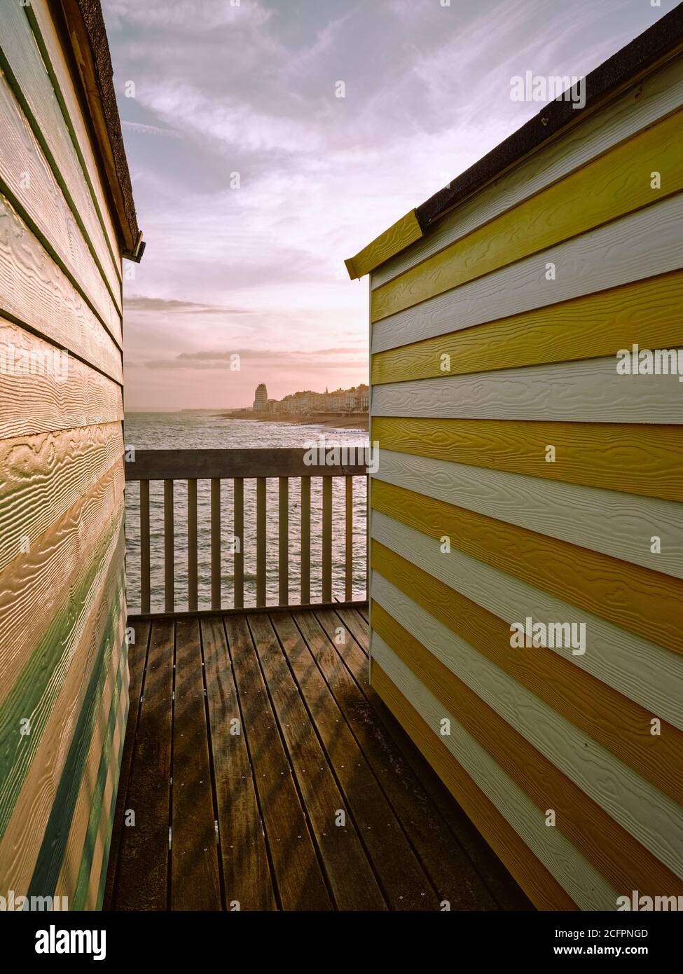 Bunt gestreifte Sommerstrandhütten und Hastings Pier in Hastings Sussex England Großbritannien Stockfoto