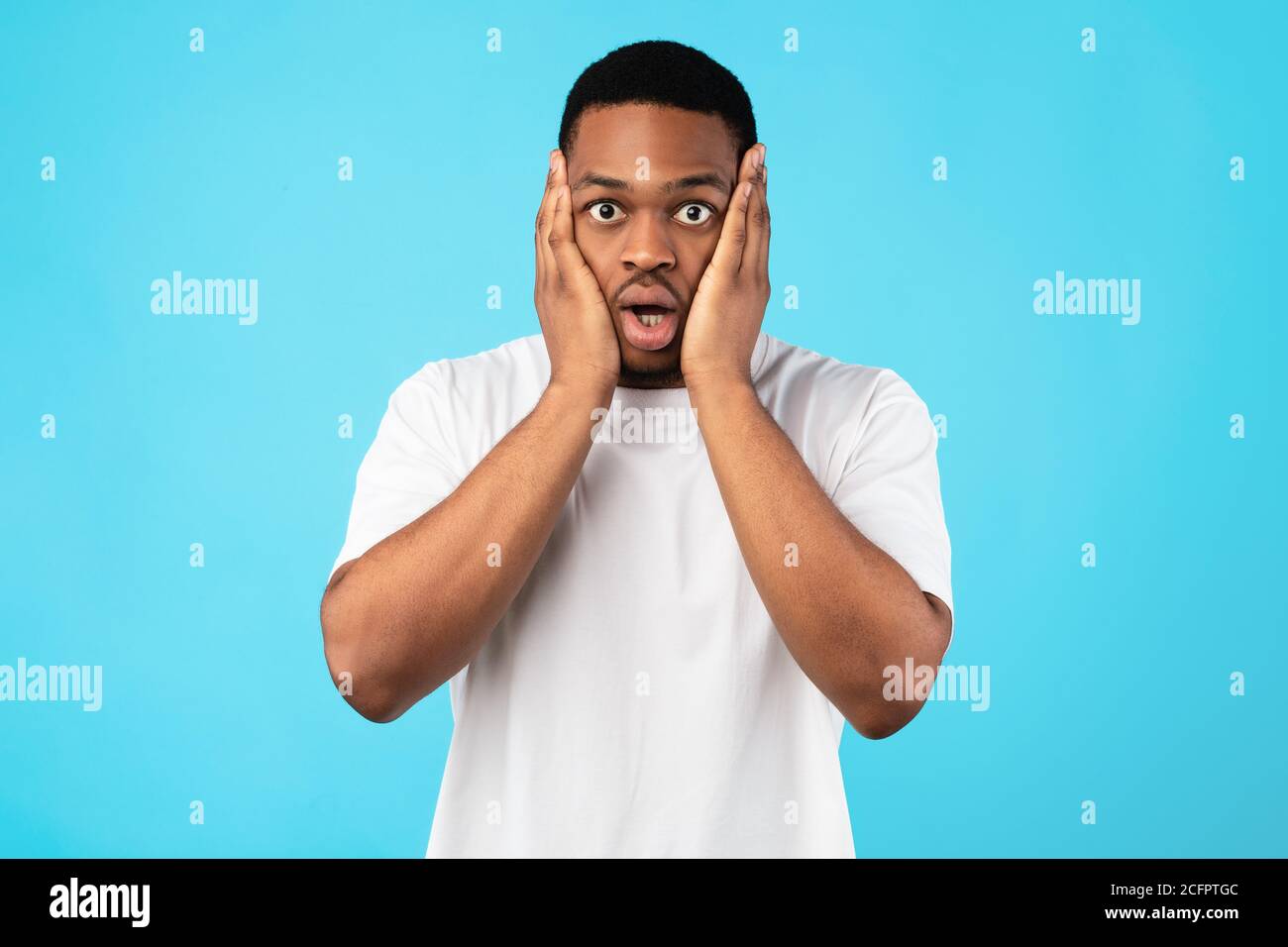 Überwältigt Black Man Schröpfende Gesicht Blick Auf Kamera, Studio Shot Stockfoto