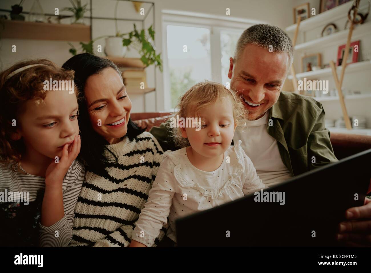 Portrait von aufgeregt glücklichen Familie mit Kindern Blick auf ein Laptop zu Hause entspannen auf der Couch entspannen - Familie Bindungszeit Stockfoto