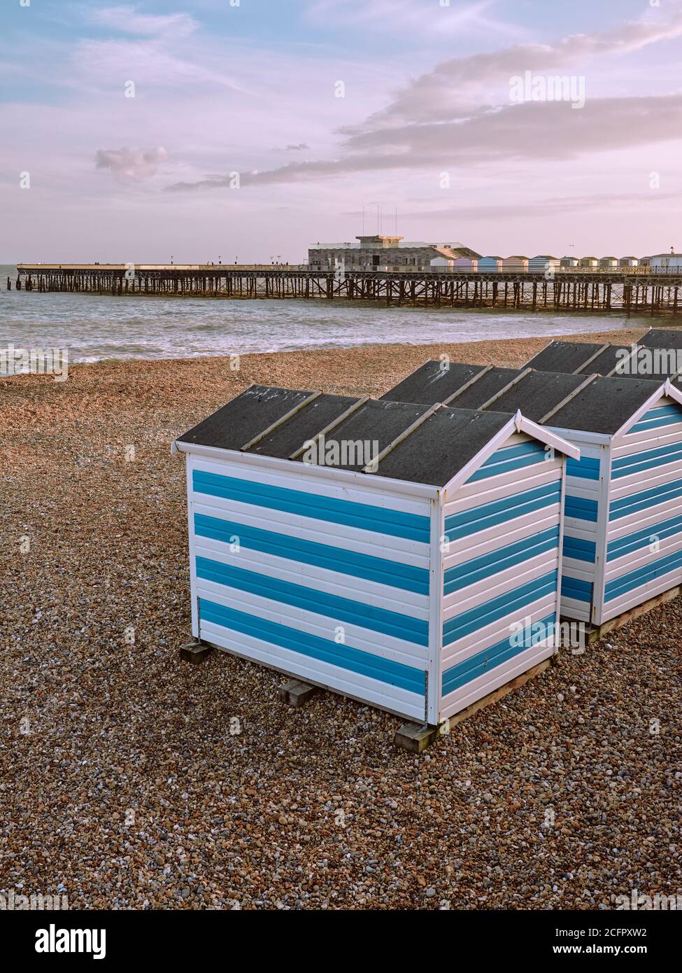Hastings Beach: Farbenfroh gestreifte Sommerstrandhütten und Hastings Pier in Hastings Sussex England Stockfoto