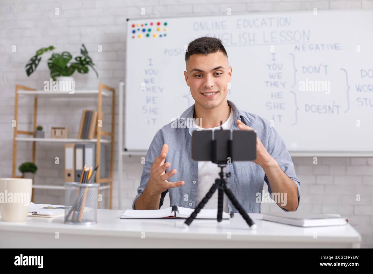 Attraktiver junger Mann erklärt englische Regeln und Gesten auf Webcam In der Klasse Stockfoto