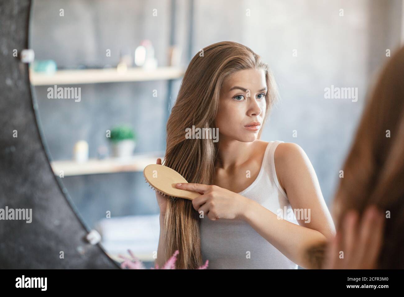 Schönes Mädchen Bürsten ihre lange schöne Haare vor Spiegel zu Hause Stockfoto