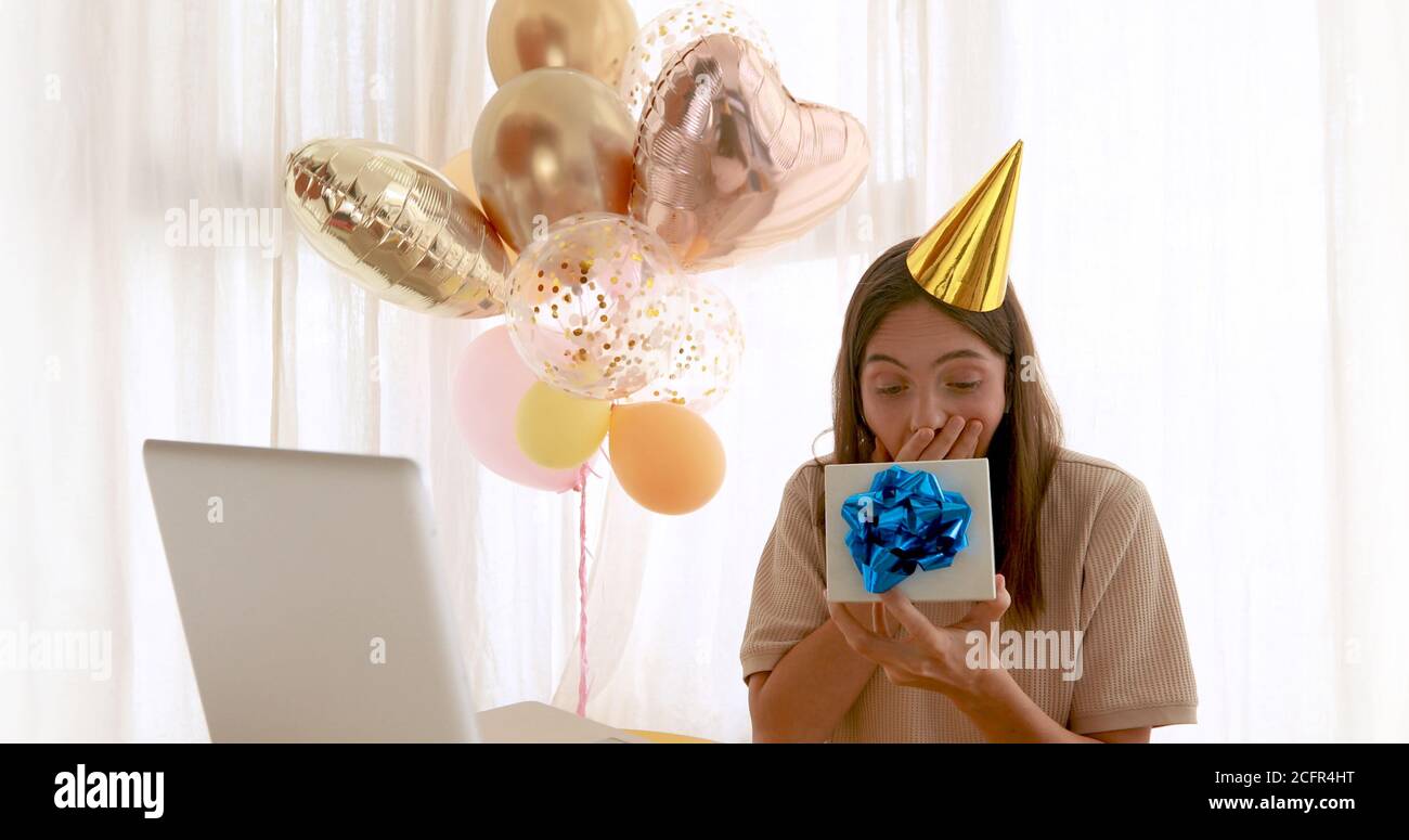 Frau öffnet Geschenk vor dem Geburtstagslaptop Stockfoto