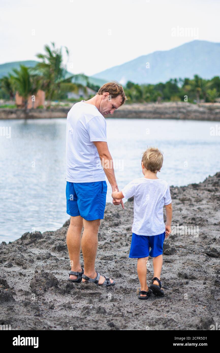 Vater kümmern sich um Sohn, während zu Fuß in der Nähe Bergsee hält führt an der Hand. Frohe Kindheit. Home natürliche Bildung, Vatertag, Papa Stockfoto