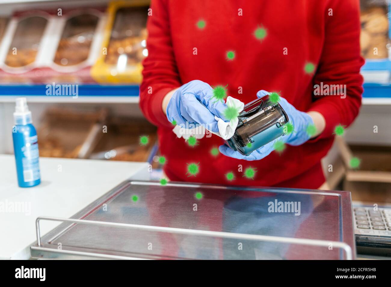 Schutz von Bakterien. Eine Frau in Gummihandschuhen behandelt das Terminal mit Antiseptikum. Im Hintergrund befinden sich Regale des Ladens. Das Konzept von coron Stockfoto