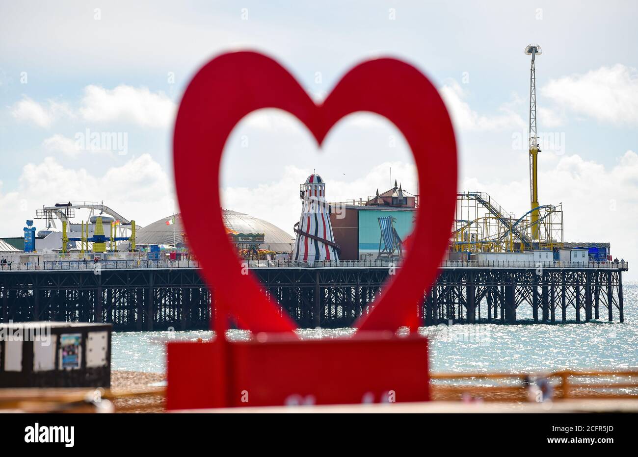 Brighton UK 7. September 2020 - Brighton Palace Pier Helter Skelter wird von einem roten Herzen umrahmt Besucher genießen die warme Herbstsonne an der Küste von Brighton heute als wärmeres Wetter für später in dieser Woche in ganz Großbritannien prognostiziert : Credit Simon Dack / Alamy Live News Stockfoto