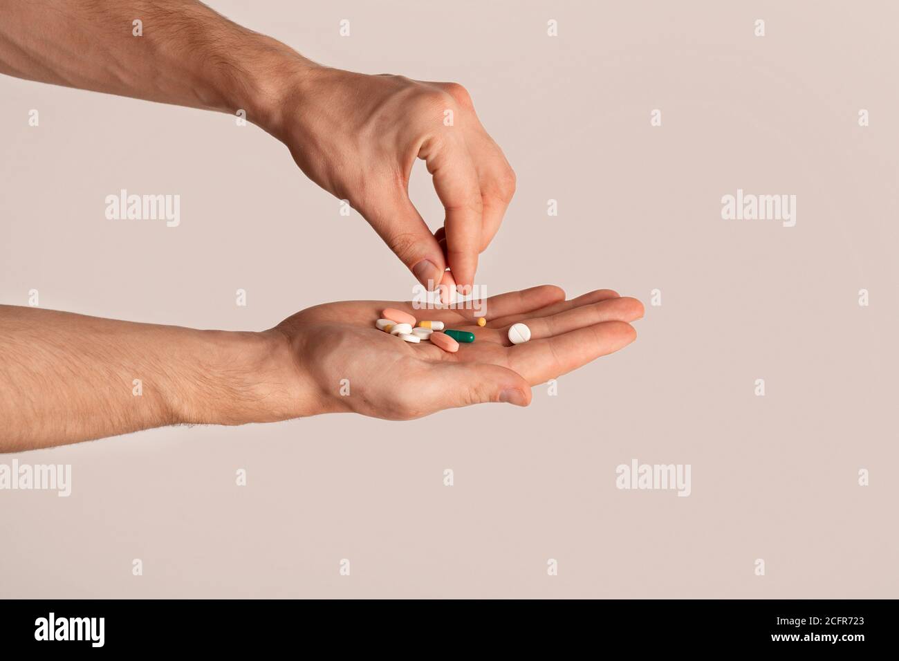 Beschnittene Ansicht von jungen Kerl hält Haufen von Pillen über hellen Hintergrund, Nahaufnahme Stockfoto