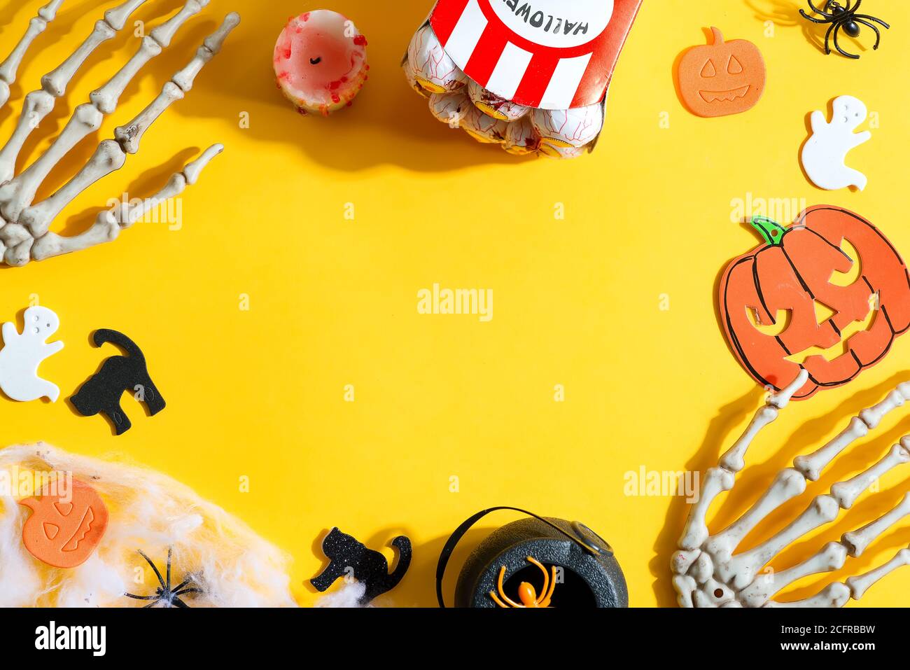 Dekorativer Rahmen für Happy Halloween Party mit Urlaubsaccessoires - Bastelkürbisse, Katzen und Geister, Skeletthände und Augäpfel Mais auf Gelb schneiden Stockfoto