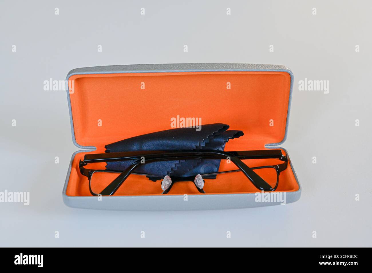 Brillen in orangefarbenem Brillenetui auf weißem Tisch Stockfoto