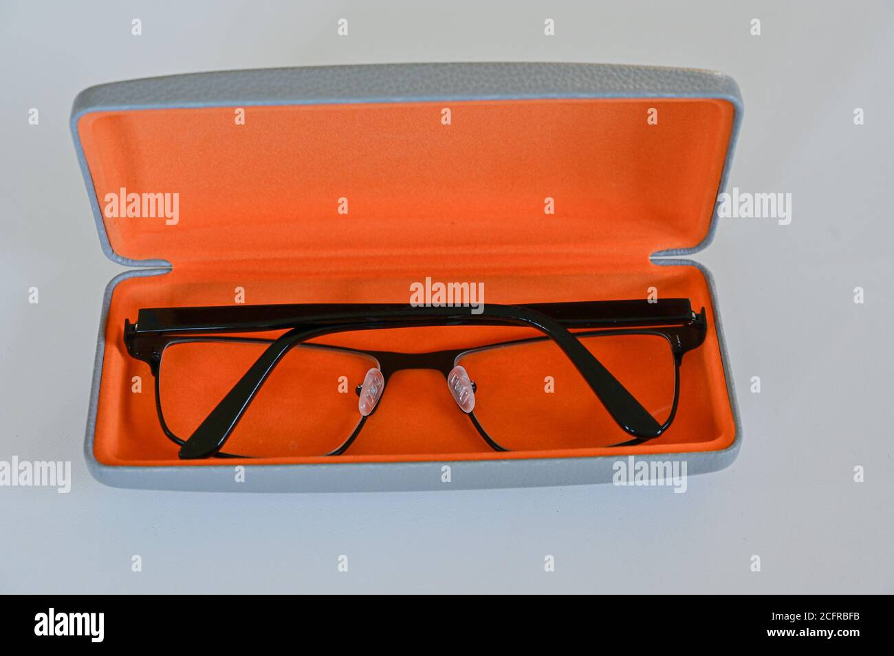 Brillen in orangefarbenem Brillenetui auf weißem Tisch Stockfoto
