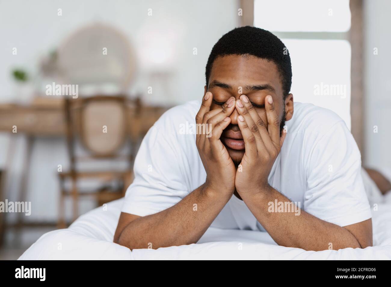 Schläfriger Afrikanischer Mann, Der Augen Reibt Und Im Bett Im Zimmer Aufwacht Stockfoto