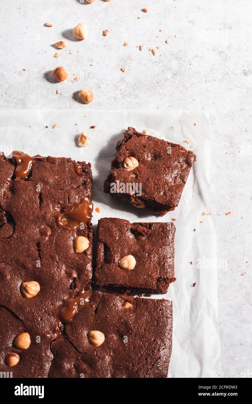 Schokoladen-Brownie mit gerösteter Haselnuss und Karamell mit zwei auf einem Stück Backpapier ausgeschnittenen Stücken. Stockfoto