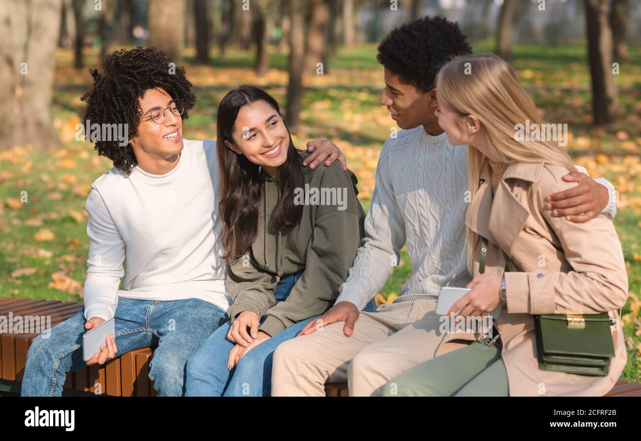 Zwei Teenager-Paare sitzen auf der Bank im öffentlichen Park Stockfoto