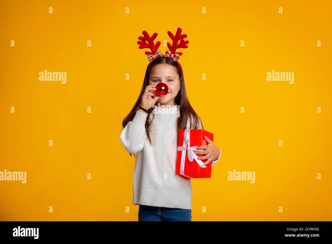 Weihnachtsgeschenk. Glücklich lustige Kind Mädchen mit Weihnachtshörnern mit Geschenk Stockfoto