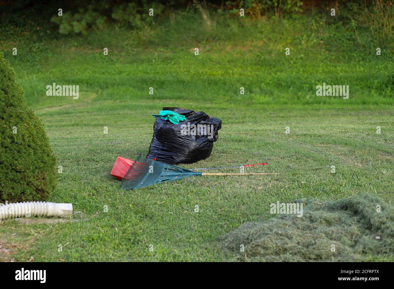 Ein Bild von einem Rechen und einem Stapel frisch Gras schneiden Stockfoto