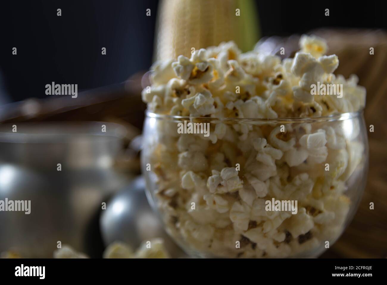 Glasschüssel mit Popcorn. Unscharfer Hintergrund. Köstlich. Kulinarische Delikatesse. Das perfekte Popcorn kann auf verschiedene Arten hergestellt werden: In der Mikrowelle, in der p Stockfoto