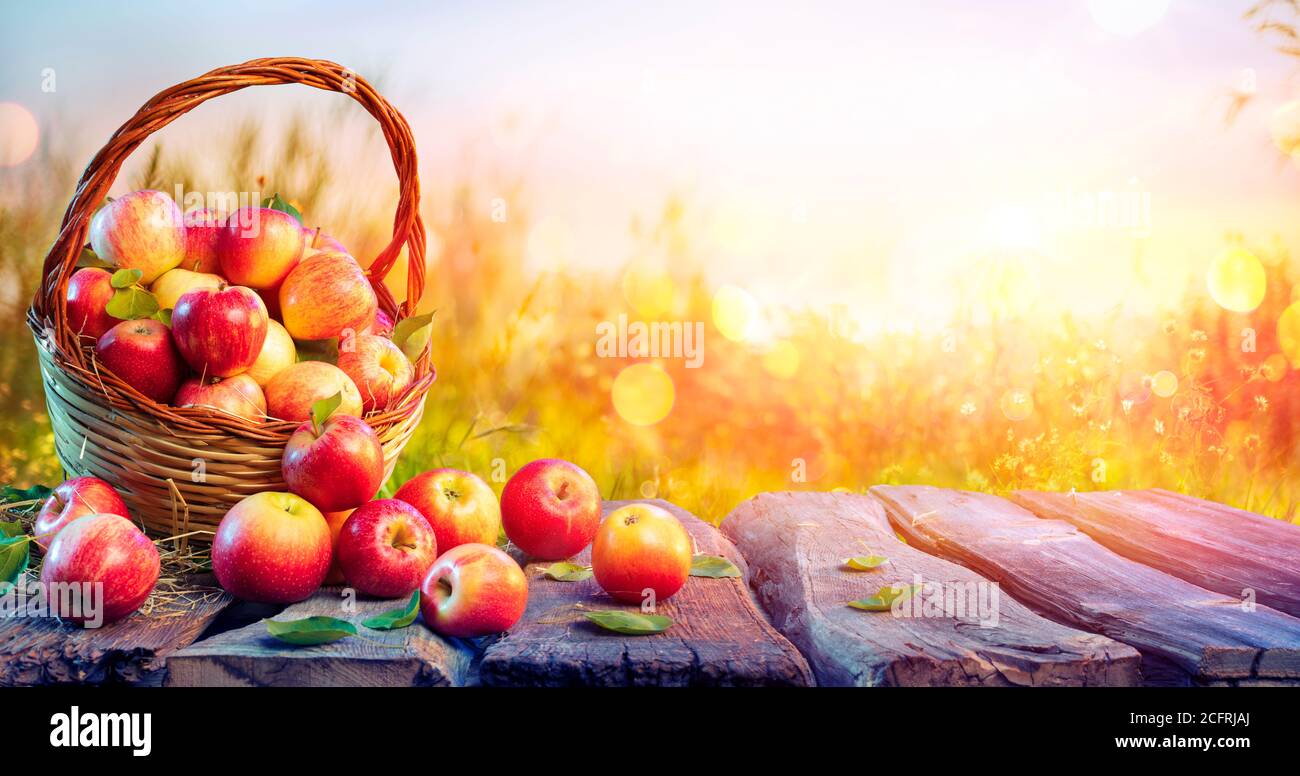 Rote Äpfel Im Korb Auf Einem Gealterten Tisch Mit Defokussierten Sonnenuntergang Im Hintergrund - Herbst Und Ernte Konzept Stockfoto