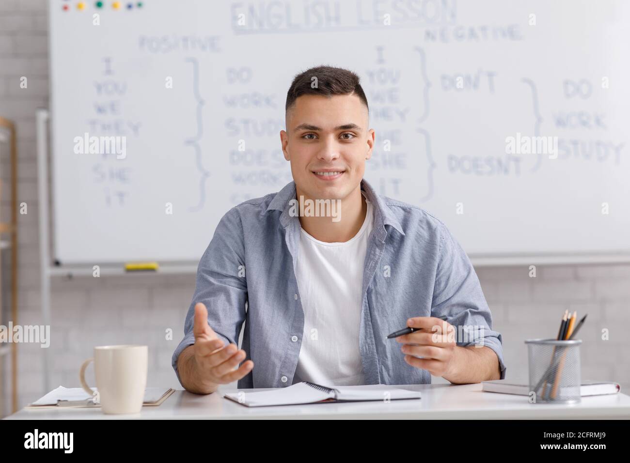 Online-Lehrer spricht per Webcam, sitzt am Tisch im Home Office und erklärt Regeln englische Grammatik Stockfoto