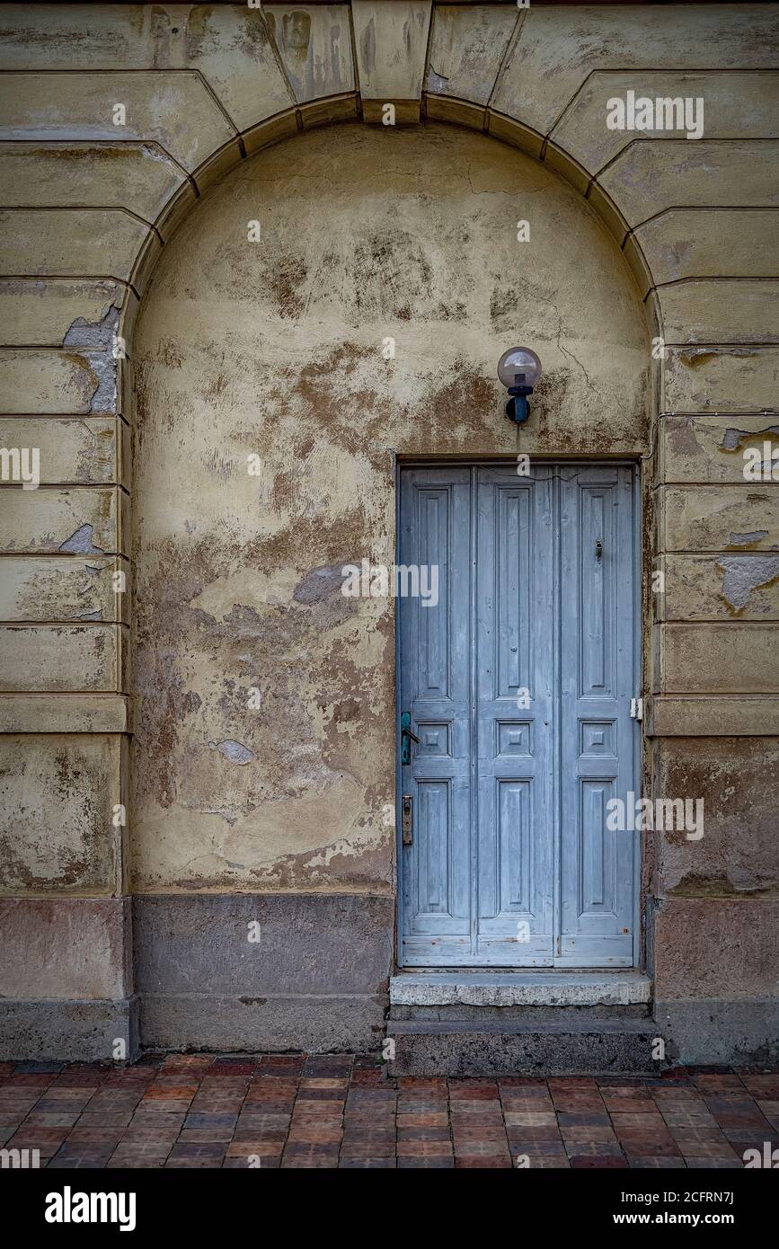 Sehr verwitterte blaue Tür in einem großen Torbogen mit gelben Wänden. Stockfoto