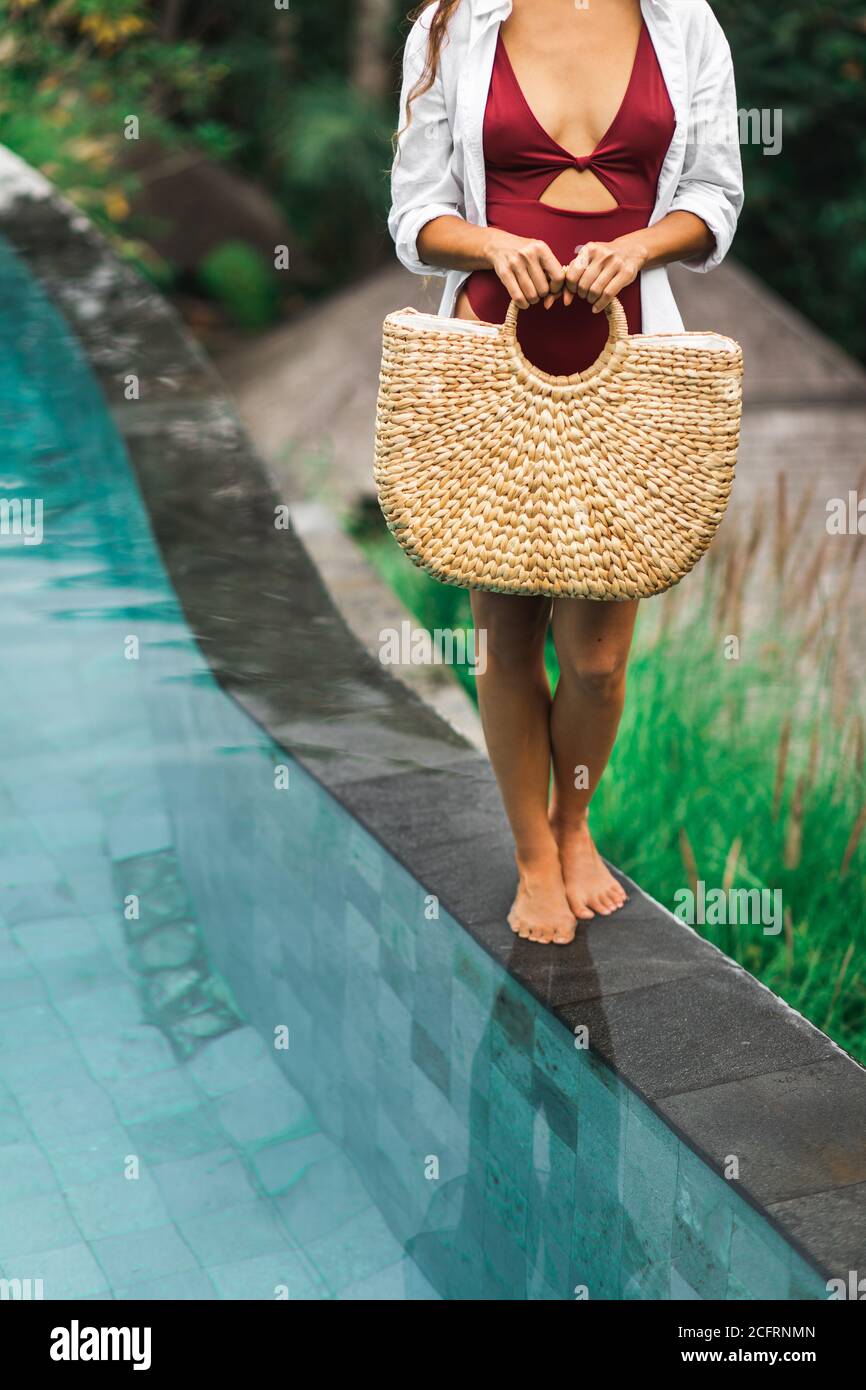 Frau in der Nähe von Schwimmbad hält in Händen handgemachte Strohweide  Strandtasche. Umweltfreundlicher und Zero Waste tropischer Lebensstil.  Organisch und natürlich, plastikfrei Stockfotografie - Alamy