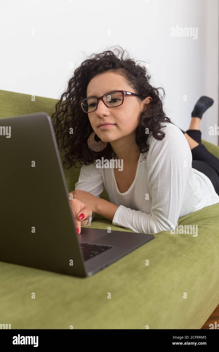 Schöne Frau, die zu Hause mit einem Computer arbeitet, mit sozialer Distanzierung arbeitet, entspannen Stockfoto