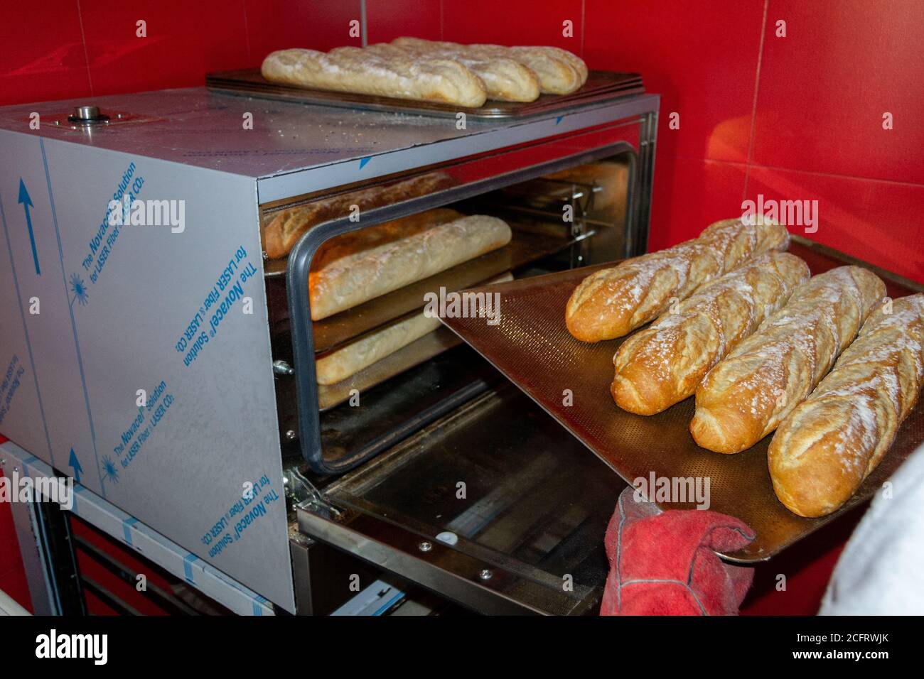 Baker Entfernen Sie die Brote aus dem Ofen einmal Sie sind bereits gebacken und mit einer gerösteten Farbe mit Rote Handschuhe Stockfoto