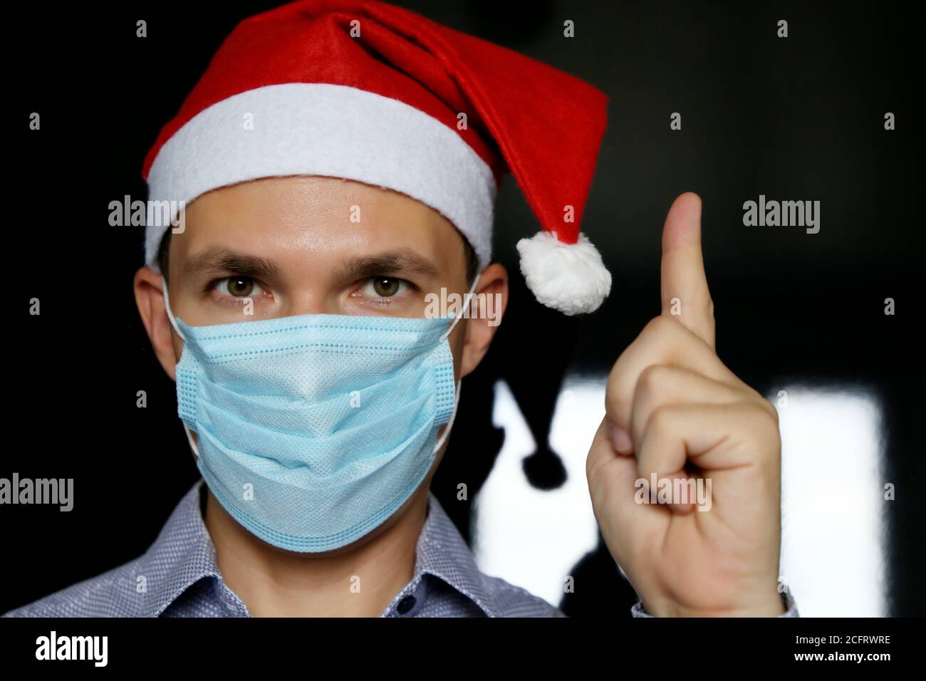 Porträt des Mannes in medizinischen Gesichtsmaske und Weihnachtsmann Hut. Weihnachtsfeier während der Coronavirus-Pandemie Stockfoto