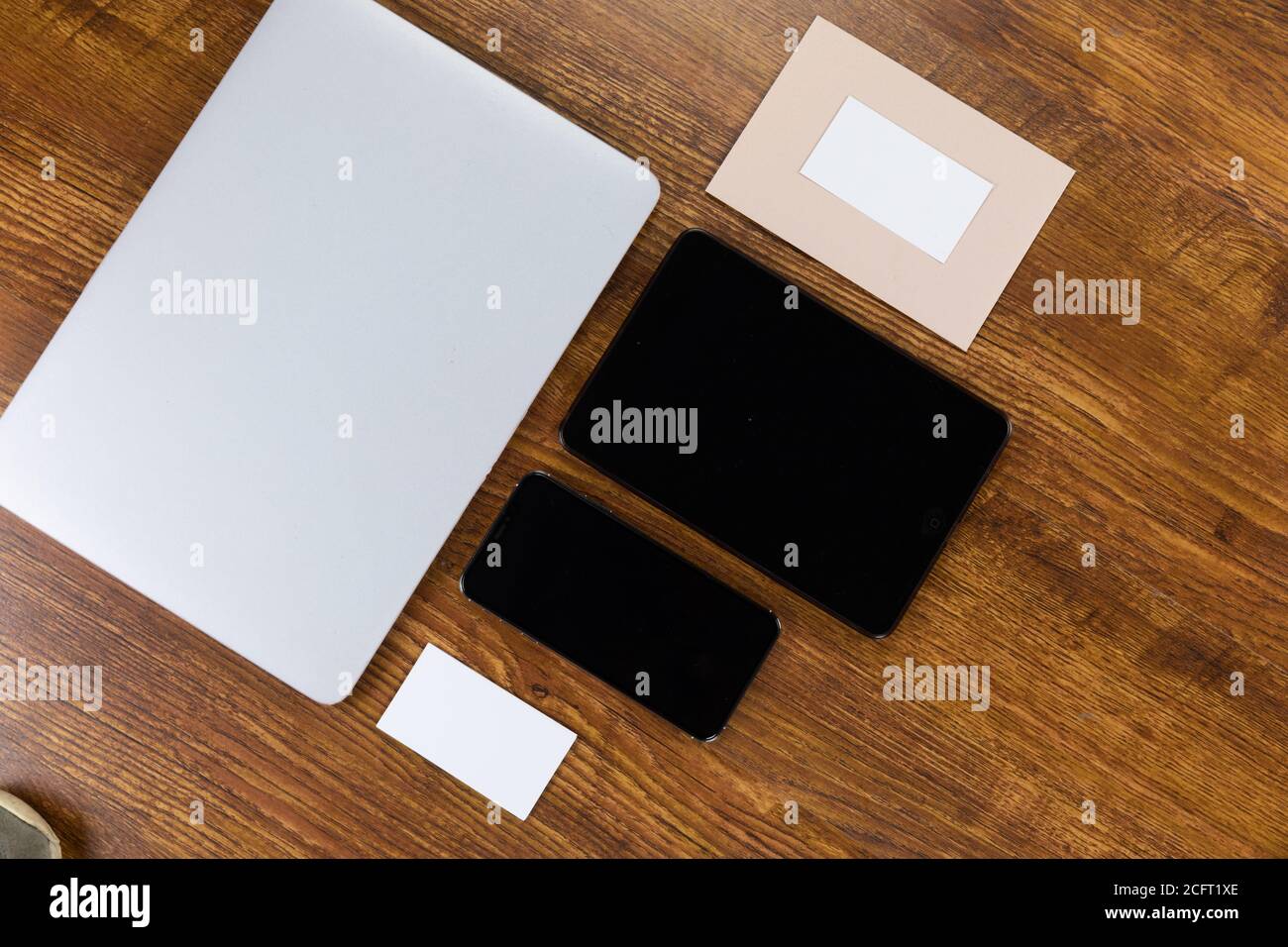 Blick auf einen Laptop mit Tablet und Smartphone, eine Kuverppe und Papier auf Holztisch Hintergrund Stockfoto