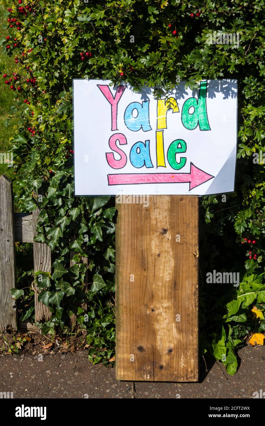 Ein buntes Schild vor einem Haus mit einem Pfeil, der auf einen Yard Sale zeigt. Stockfoto