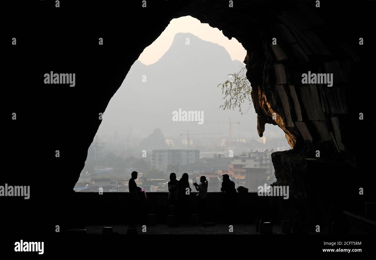 Mt Diecai, Guilin, Provinz Guangxi, China. Der Blick von einer Höhle auf dem Weg zum Gipfel des Mt Diecai mit nicht identifizierbaren Menschen in Silhouette. Stockfoto