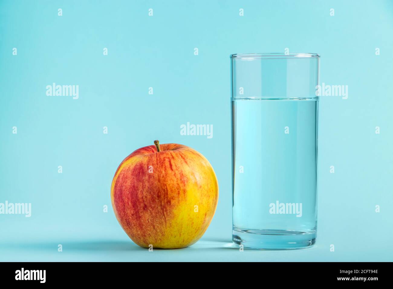 Apfel und Glas reines Wasser auf blauem Hintergrund. Gesundheit und Ernährung Konzept, Ort für Text. Stockfoto