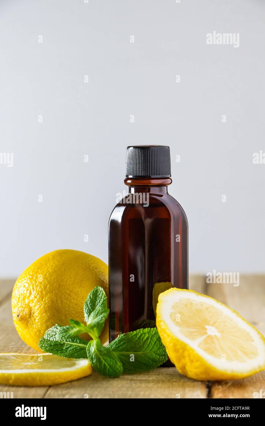 Kosmetik für Spa-Therapie. Flasche aromatisches Öl mit Zitrone und Minze auf Holzgrund. Stockfoto