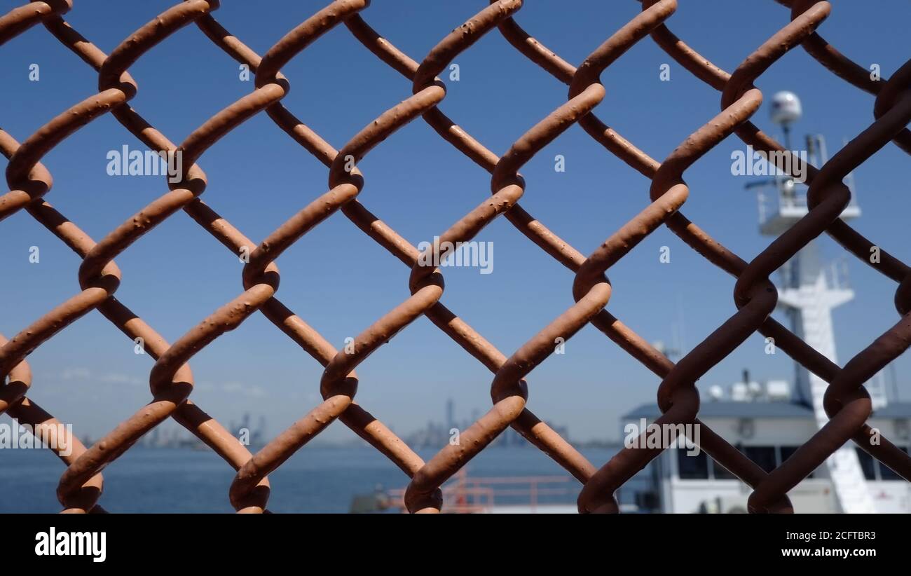 USA, New York. Wall Street Büroturm fotografiert durch Kettengliederzaun der Staten Island Ferry Stockfoto