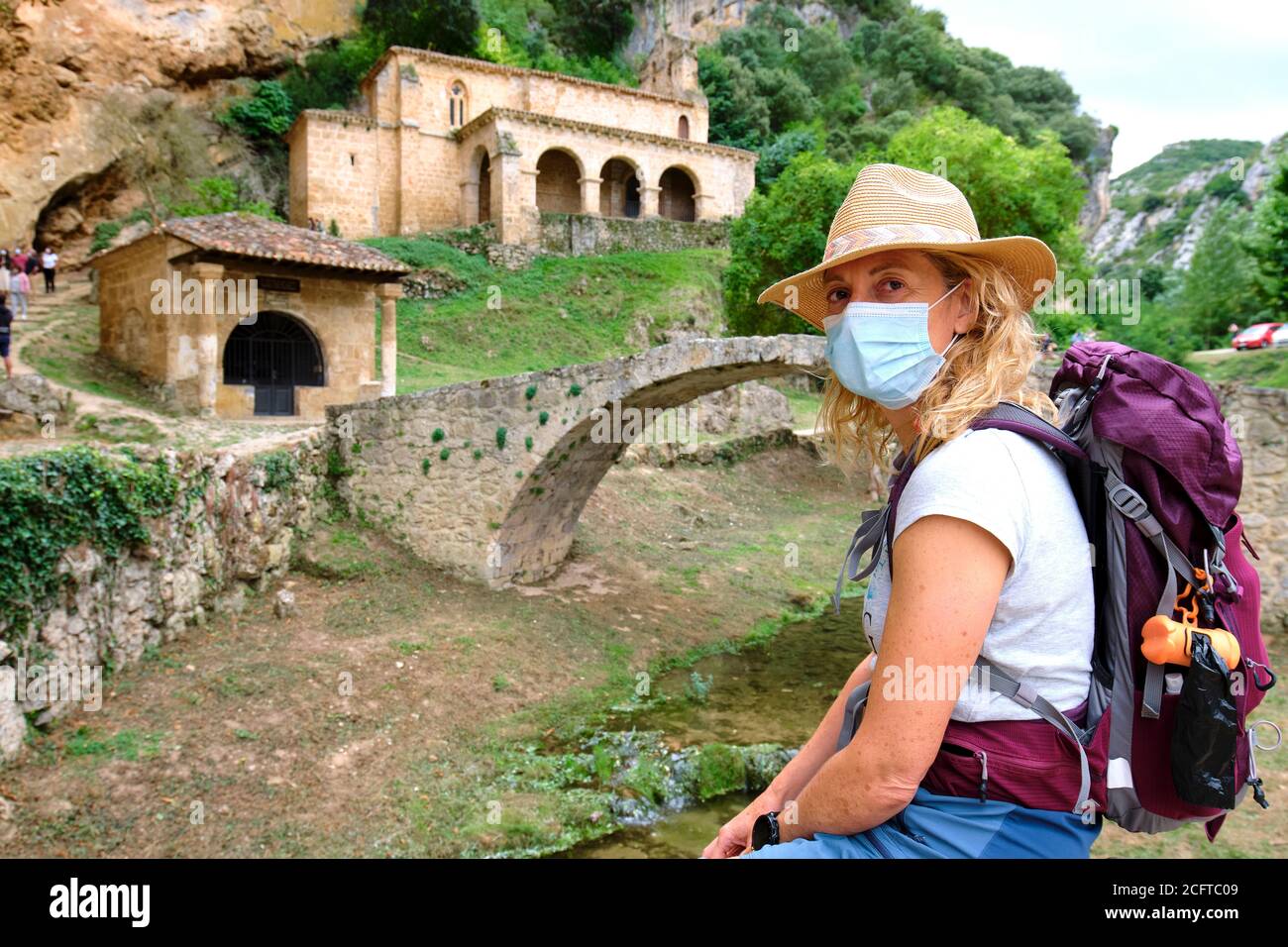 Wanderer reife junge Frau mit einer Gesichtsmaske in der Nähe einer alten Kapelle. Stockfoto