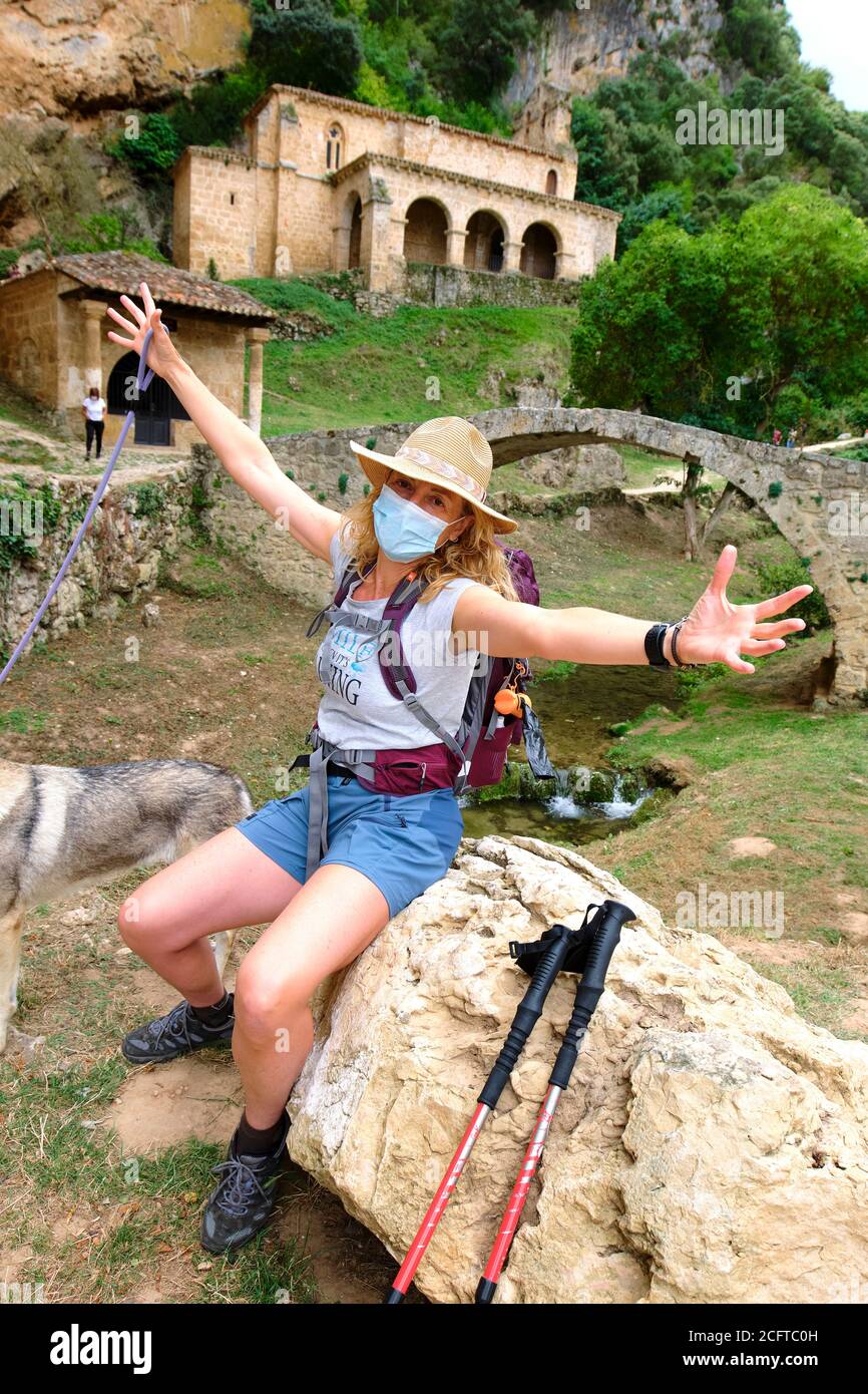 Wanderer reife junge Frau mit einer Gesichtsmaske in der Nähe einer alten Kapelle. Stockfoto