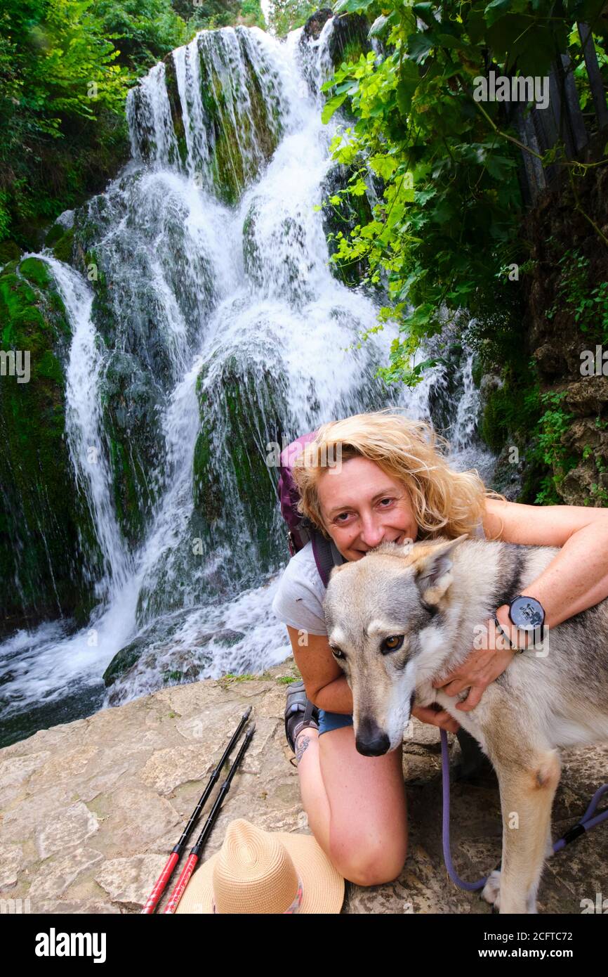 Wanderer reife junge Frau mit einem Hund und Wasserfall. Stockfoto