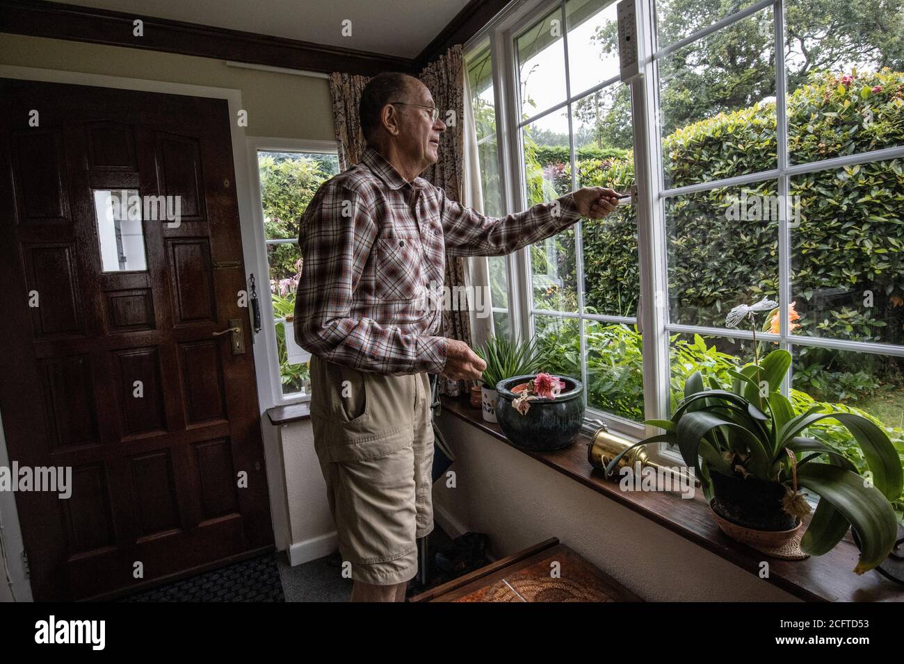 Ältere Paar saß in ihrer Veranda soziale Distanzierung zu Hause während der Coronavirus Pandemie Lockdown, Wales, Vereinigtes Königreich Stockfoto