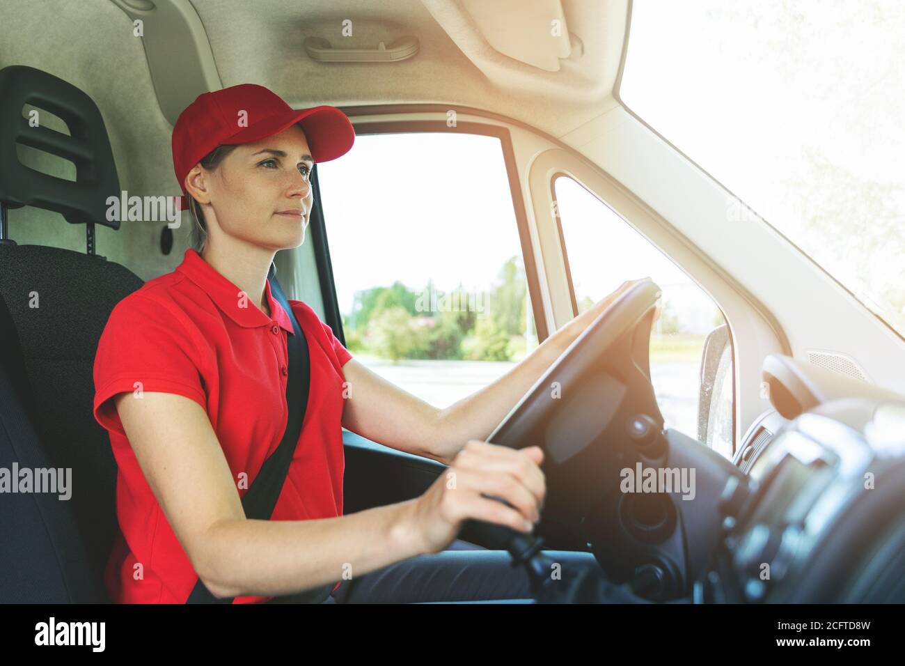 Transport-Dienstleistungen - junge Frau in roten Uniform fahren van Stockfoto