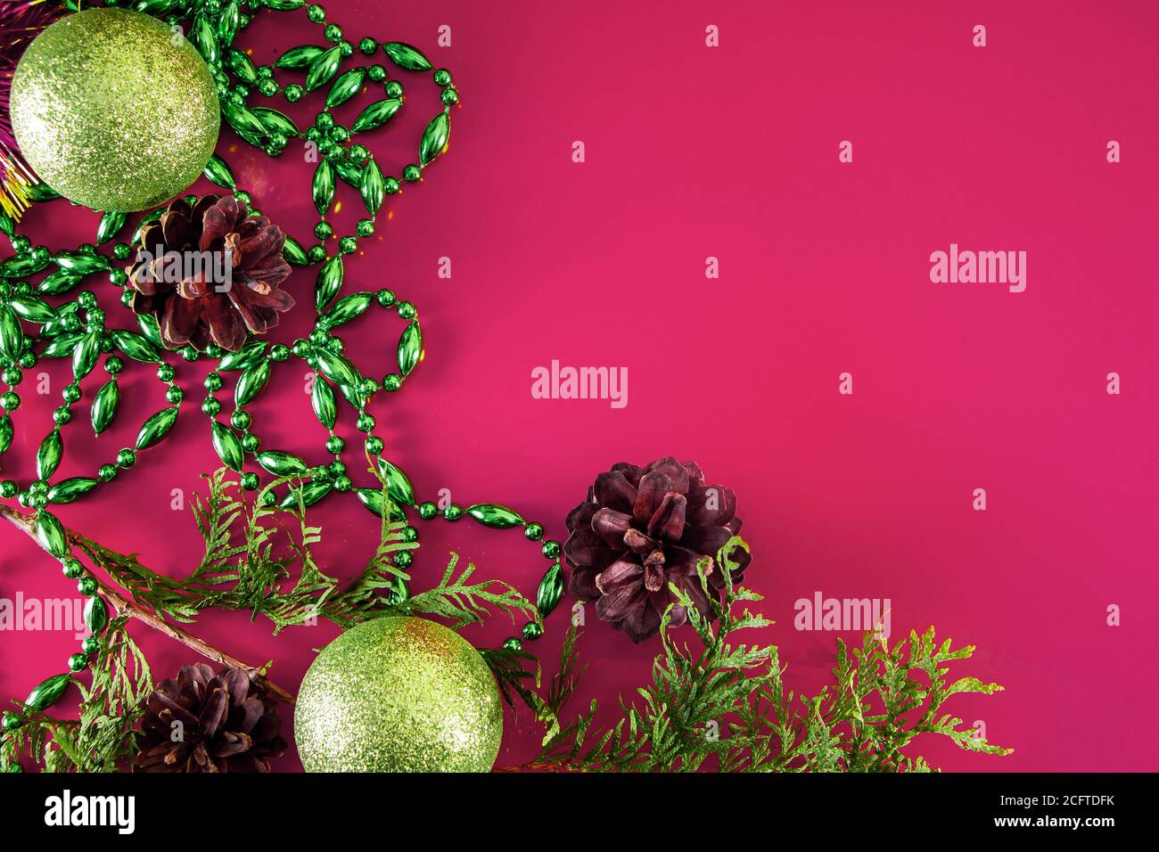 Weihnachtsdekor - Kegel, Weihnachtskugeln und Zweige auf einem rosa Hintergrund. Duftkerze für einen angenehmen Urlaub. Ort für Ihren Text. Stockfoto