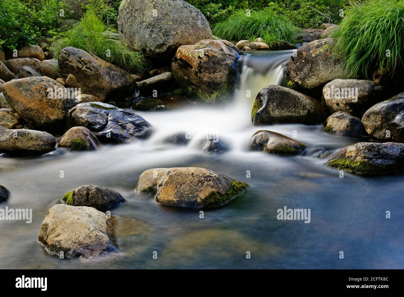 Zeitbezogene Exposition eines Wasserfalls zwischen nassen Felsen Stockfoto