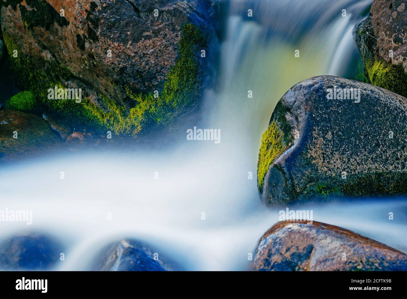 Zeitbezogene Exposition eines Wasserfalls zwischen nassen Felsen Stockfoto