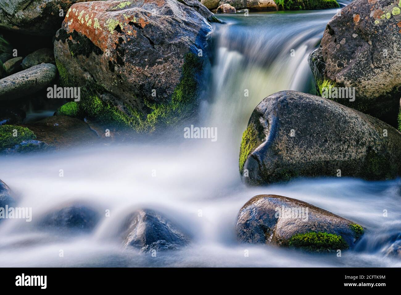 Zeitbezogene Exposition eines Wasserfalls zwischen nassen Felsen Stockfoto