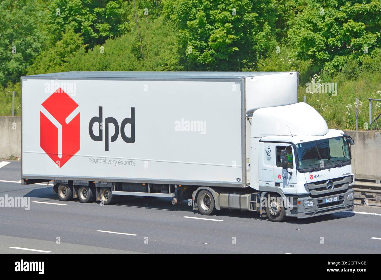 LKW-Fahrer & Fahrerhaus dpd Paketzustellung Transport Geschäft Mit Marken- und Logo-Werbung auf der Seite des Sattelaufliegers Fahren Sie auf der britischen Autobahn Stockfoto